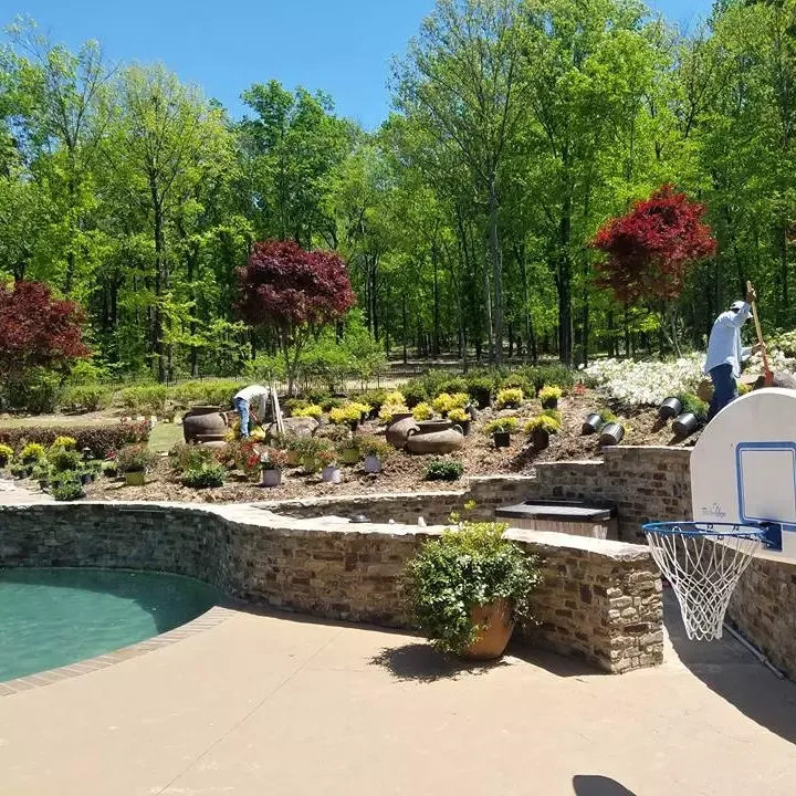 Crew planting and mulching beds around a pool