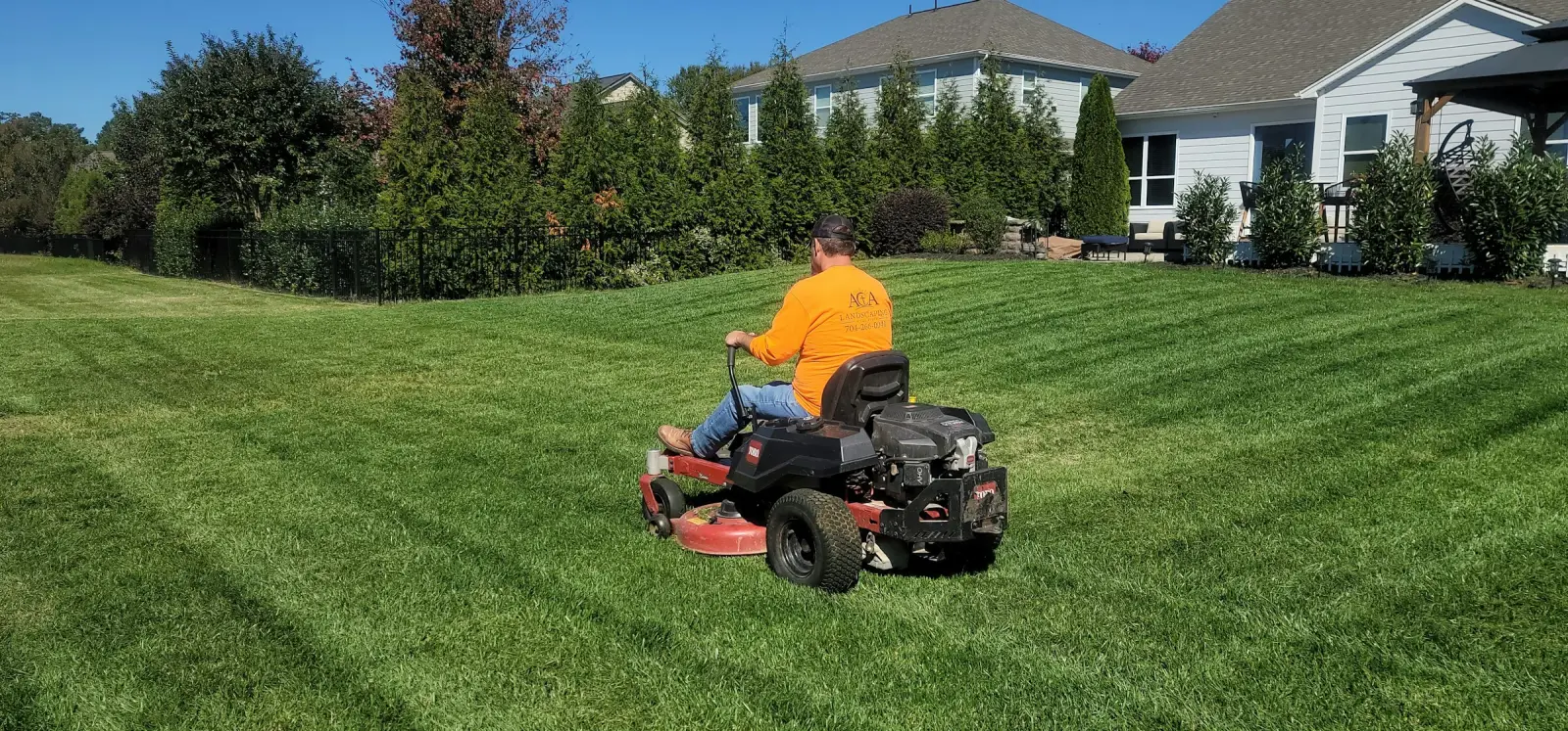 Riding mower cutting stripes into a backyard lawn