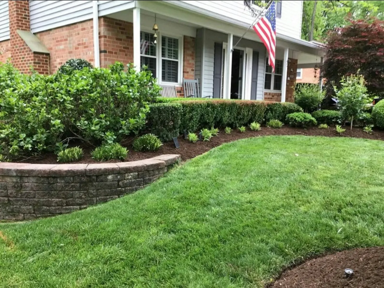 Fresh mulch beds and green lawn in front of a brick home